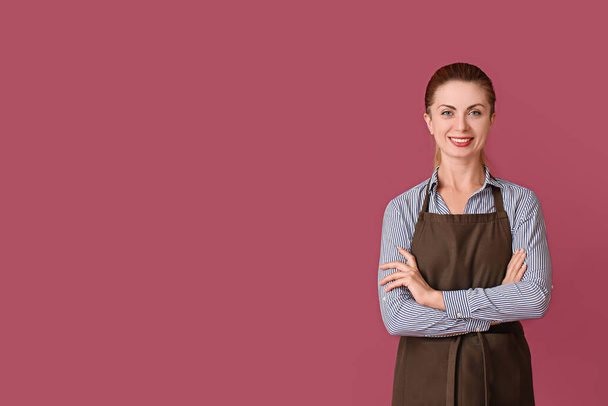 Beautiful young woman wearing apron on color background - Photo, Image