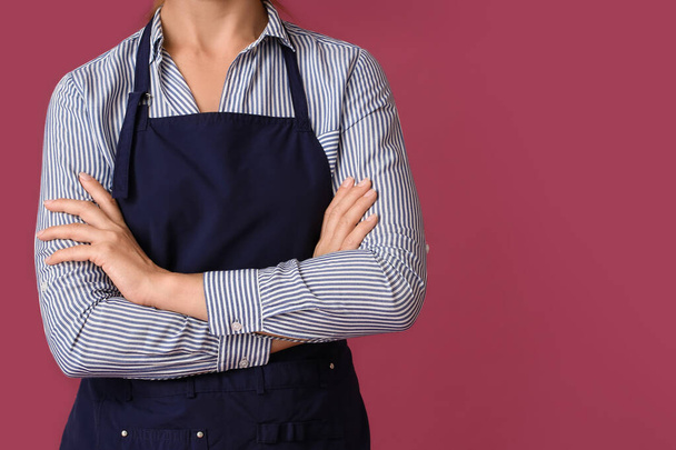 Young woman wearing apron on color background - Photo, Image