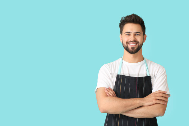 Young man wearing apron on color background - 写真・画像
