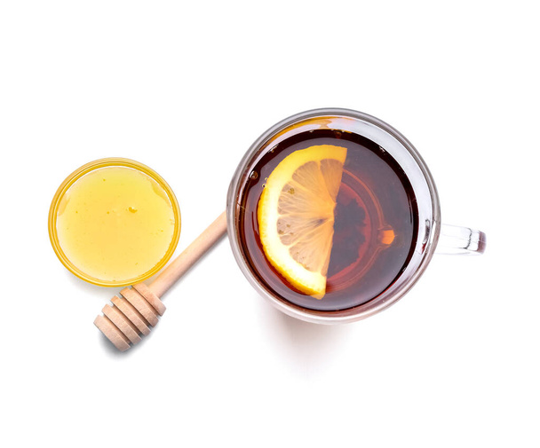 Coupe en verre de thé noir chaud avec du citron et du miel sur fond blanc - Photo, image