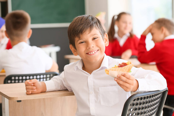 Schoolboy with sandwich in classroom - Foto, imagen