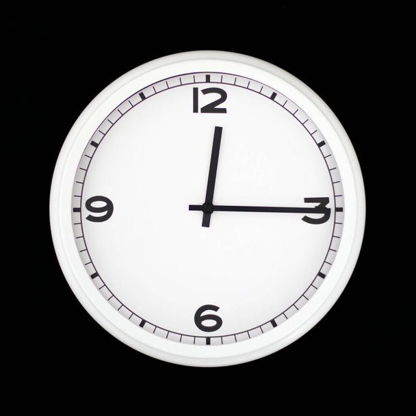 White round analog wall clock isolated on black background, its quarter past twelve. - Photo, Image
