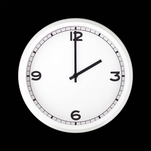 White round analog wall clock isolated on black background, its two oclock. - Photo, Image