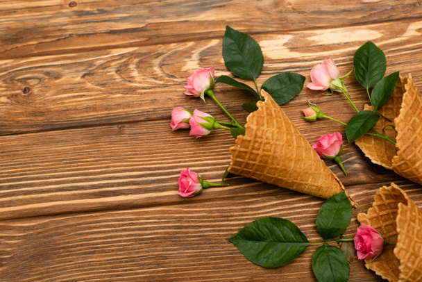 top view of pink flowers in waffle cones on wooden surface - Fotografie, Obrázek