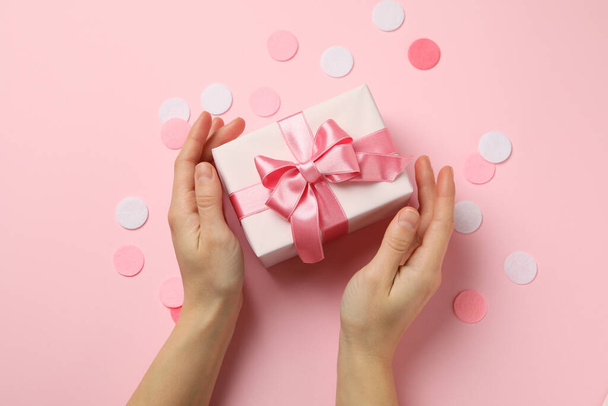 Female hands holding gift box on pink background - Photo, Image