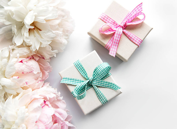 Composición festiva sobre fondo blanco: flores de peonías, cajas de regalo. Vista superior, espacio de copia. - Foto, imagen