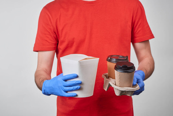 Entrega homem segurando uma caixa de macarrão wok e xícaras de café - Foto, Imagem