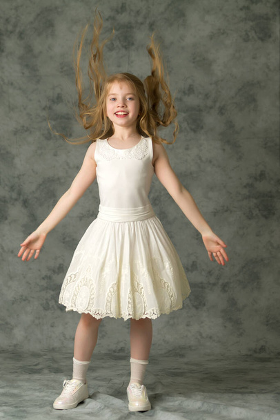 A beautiful little girl straightens her hair on her head. - Valokuva, kuva
