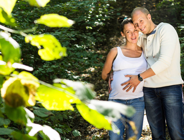 Man taking care of pregnant woman and smiling together at camera - Valokuva, kuva