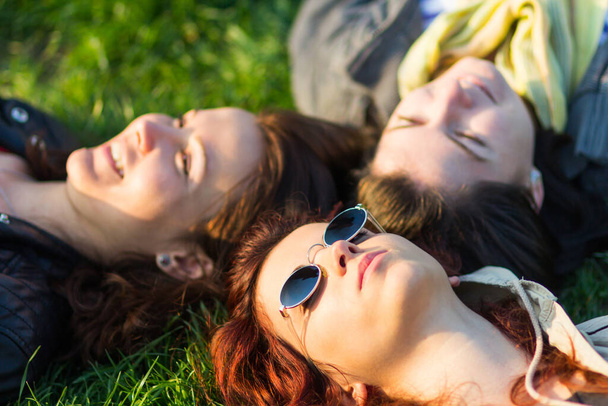 Portrait of three woman lying on the grass and enjoying the sun  - Foto, afbeelding