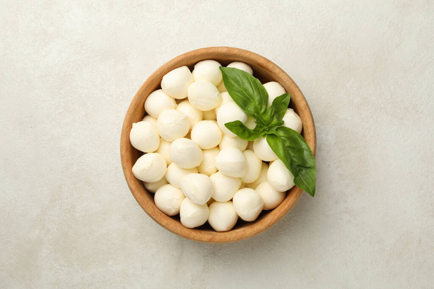 Bowl with mozzarella and basil on white textured background, top view - Photo, Image