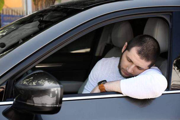 Tired man sleeping in his modern car - Foto, afbeelding