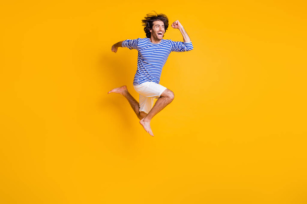 Full body photo of excited guy jump run fast wear nautical vest isolated over shine yellow color background - Foto, afbeelding