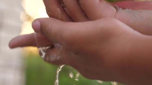 Een man wast zijn handen met water in de straat close-up. Spatten schoon water onder de handpalmen, handen wassen. Hygiëne en hygiëne gezondheidsconcept. Gezond kind. Op straat wassen.. - Video