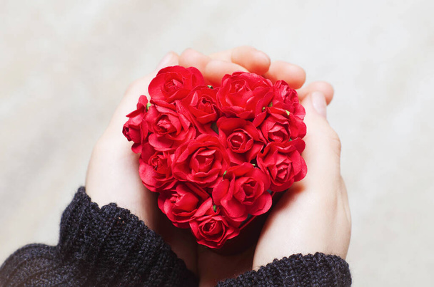 Valentin napi ajándék koncepció. Női kéz kezében piros szív alakú doboz papír rózsa . - Fotó, kép