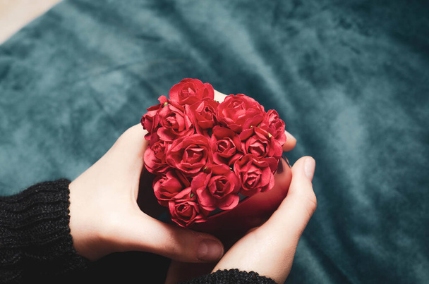 Sevgililer Günü hediye konsepti. Kırmızı kalp şeklinde kağıt güllerle dolu bir kutu tutan kadın elleri. . - Fotoğraf, Görsel