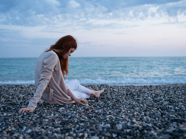 femme sur une plage rocheuse dans un pull et l'océan en arrière-plan. Photo de haute qualité - Photo, image