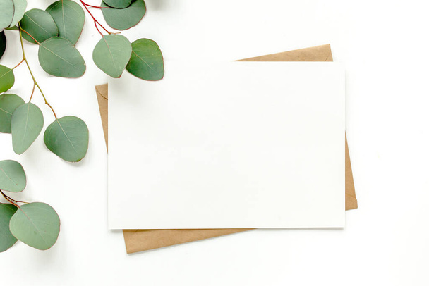 Mockup invitation, blank greeting card and green leaves eucalyptus. Flat lay, top view. - Zdjęcie, obraz