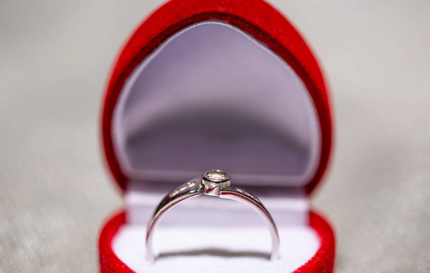 Close-up van een witgouden verlovingsring met diamanten in de rode doos, liefdesconcept - Foto, afbeelding