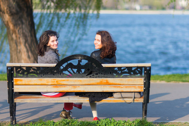 Best female friends sitting on a bench on a sunny day - Φωτογραφία, εικόνα