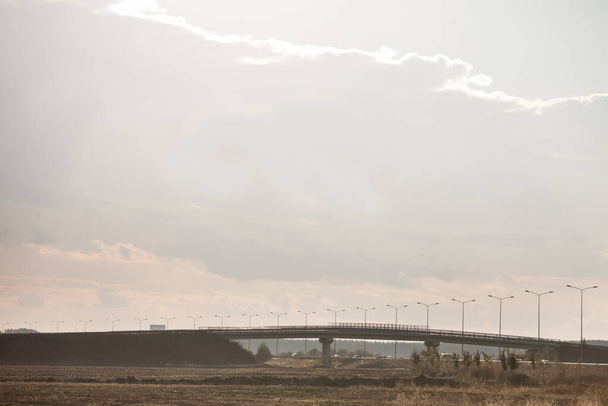 Venkovská krajina s nově vybudovanou dálniční silnicí s dopravou projíždějící přes betonový most během západu slunce - Fotografie, Obrázek