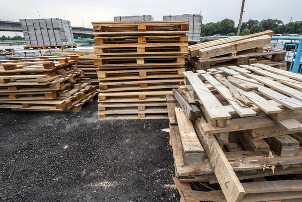 Pile di pellet di legno, alcuni danneggiati, pronti per il riciclaggio, impilati in un cantiere di un magazzino, utilizzati per la spedizione e il trasporto di carico e materiale. - Foto, immagini