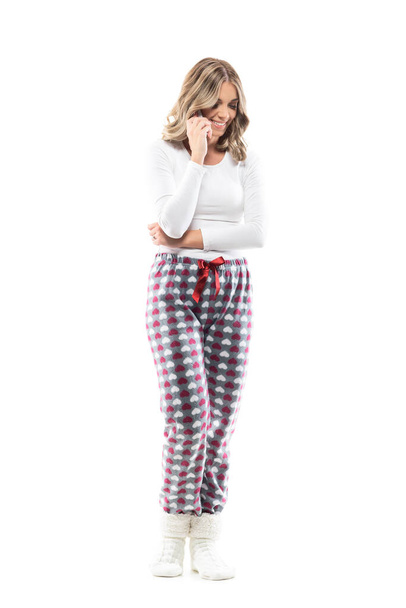 Beautiful young woman in leisure home clothes and pajama speaking on the phone and smiles. Full length portrait on white background. - Photo, Image