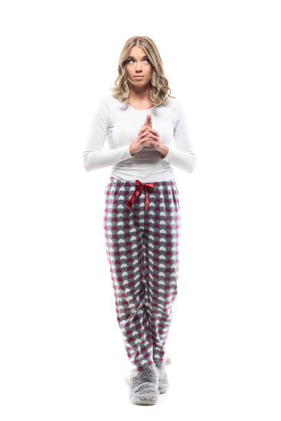 Young pretty woman in pajama and fluffy slippers looking away planning with interlaced fingers. Full length portrait on white background. - Photo, Image