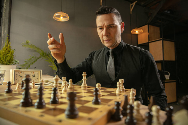 Ernsthafter Schachspieler sitzt zu Hause und spielt allein Schach. - Foto, Bild