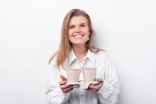 Veselá mladá žena v bílé košili drží dva šálky kávy odnést - Fotografie, Obrázek