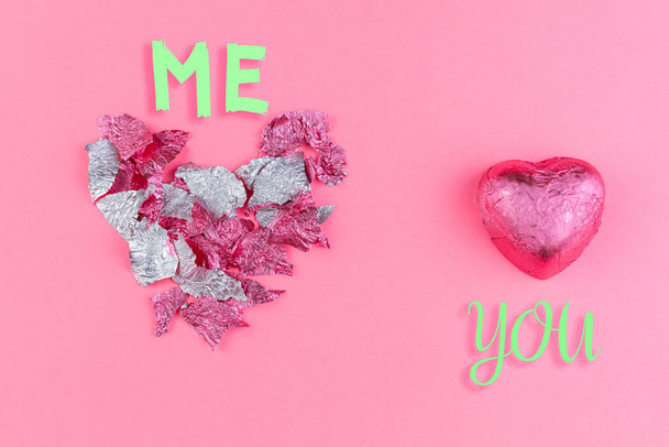 Concept of 14 february or Valentine's Day. Chocolate candy-a heart in a pink wrapper, and a torn wrapper in the form of a heart from the candy. Pink background. Copy space. Me and you. - Fotoğraf, Görsel