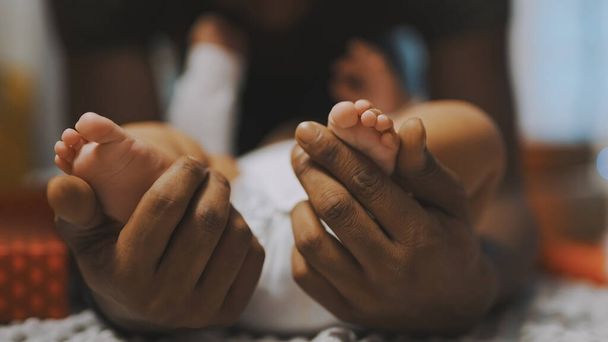Close up, baby feet. Father and son bonding. African american man playing with little feet of his mulatto baby - Фото, зображення