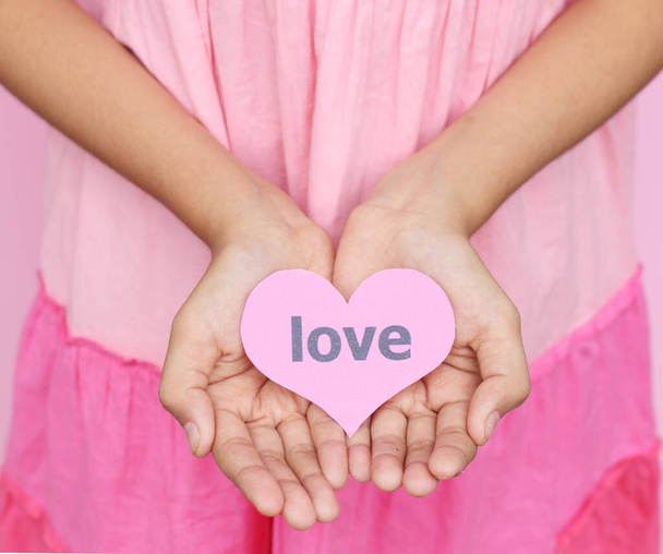Love concept - jong meisje dragen roze jurk geven de hand met hart tag van liefde naar een andere, Valentijnsdag - Foto, afbeelding