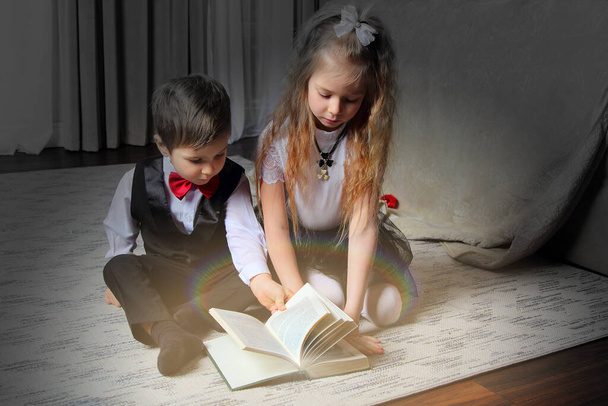 τα παιδιά ανοίγουν ένα μαγικό βιβλίο που λάμπει με ένα λαμπρό φως - Φωτογραφία, εικόνα