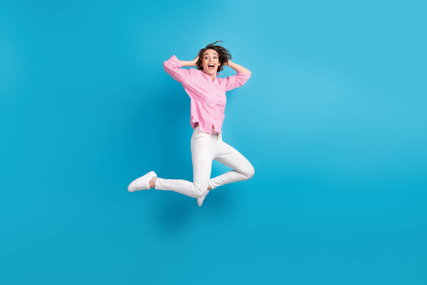 Full size photo of crazy impressed girl jump touch hands head isolated over blue pastel color background - Foto, afbeelding