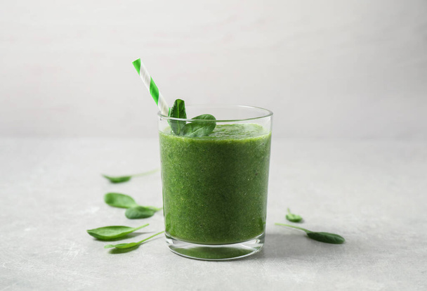 Green juice and fresh spinach leaves on light grey table - Foto, Imagen
