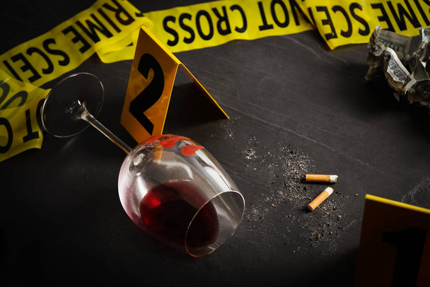 Wine glass with fingerprints and stubs on black slate table. Crime scene - Zdjęcie, obraz