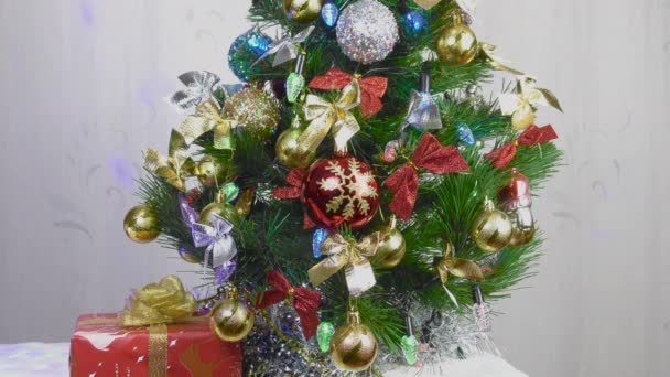 Close-up de brinquedos de Natal em uma árvore de Natal verde e um presente sob ele - Filmagem, Vídeo