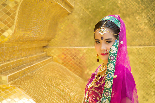 Close up retrato encantador mulher asiática vestindo um saree tradicional indiano roxo com um fundo de parede dourada. - Foto, Imagem