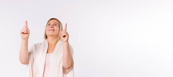 Banner. A woman with a happy smile looks up and shows her index fingers. White background and empty space. - Photo, Image
