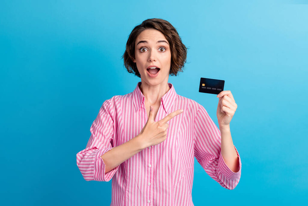 Photo of astonished lady point index finger credit card with salary wear formal white pink shirt isolated over blue color background - Fotografie, Obrázek