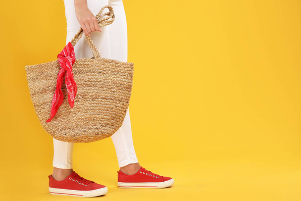 Young woman with stylish straw bag on yellow background, closeup. Space for text - Foto, Imagen