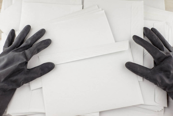 the threat in an envelope: People in protective impermeable gloves collects anonymous envelopes for checks for dangerous content, poisons, biological weapons - Photo, Image