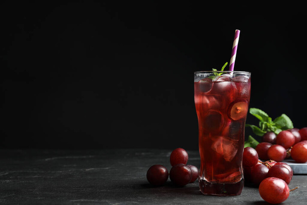 Delicious grape soda water on black table, space for text. Refreshing drink - Фото, изображение