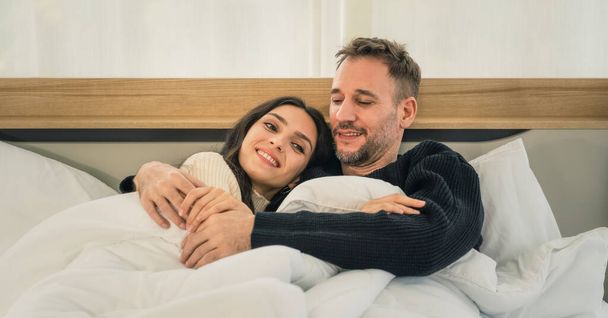 caucasian married couple husband and wife having romantic moment together on bed at home in winter - Foto, afbeelding
