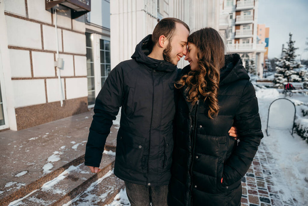Mutlu adam ve kız karla kaplı şehirde yürür ve birbirlerine nazikçe gülümserler. - Fotoğraf, Görsel