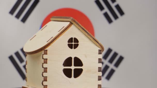 Small wooden house, Republic of Korea flag on background. Real estate concept, soft focus - Footage, Video