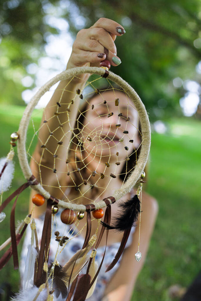 Traumfänger in Mädchenhand hinter dem Gesichtsporträt im Freien - Foto, Bild