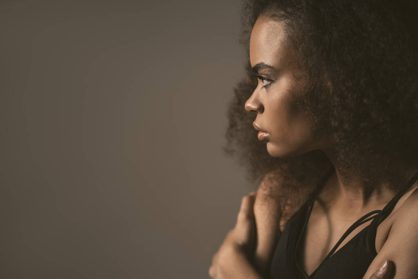 Sad or after breaking up with boyfriend African American girl standing in black top isolated on grey background. Human emotions, facial expression concept - Фото, изображение