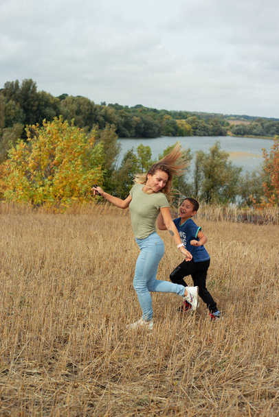 母と息子の若者が一緒に歩いていて、秋の時間に楽しい野外活動をしています  - 写真・画像